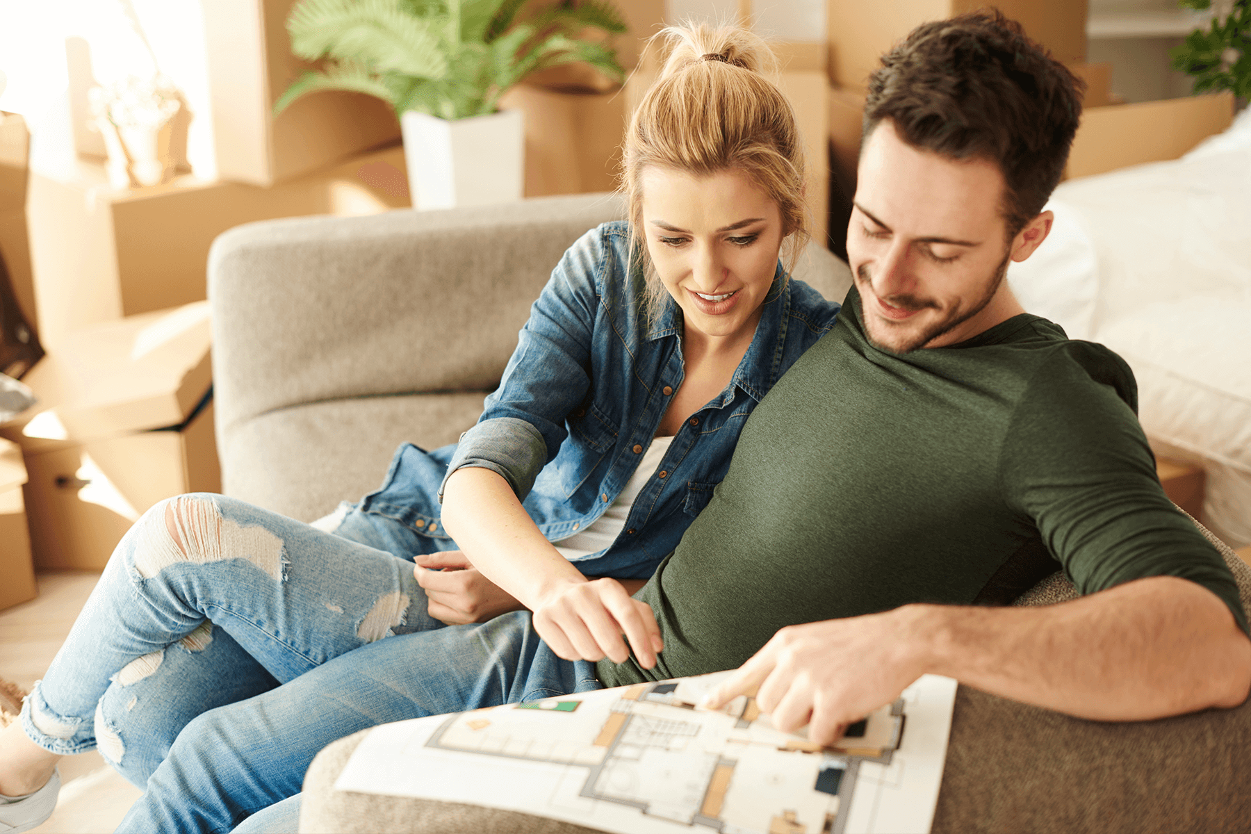 Paar liest entspannt auf der Couch einen ausgedruckten Grundriss. Maximale Individualität.