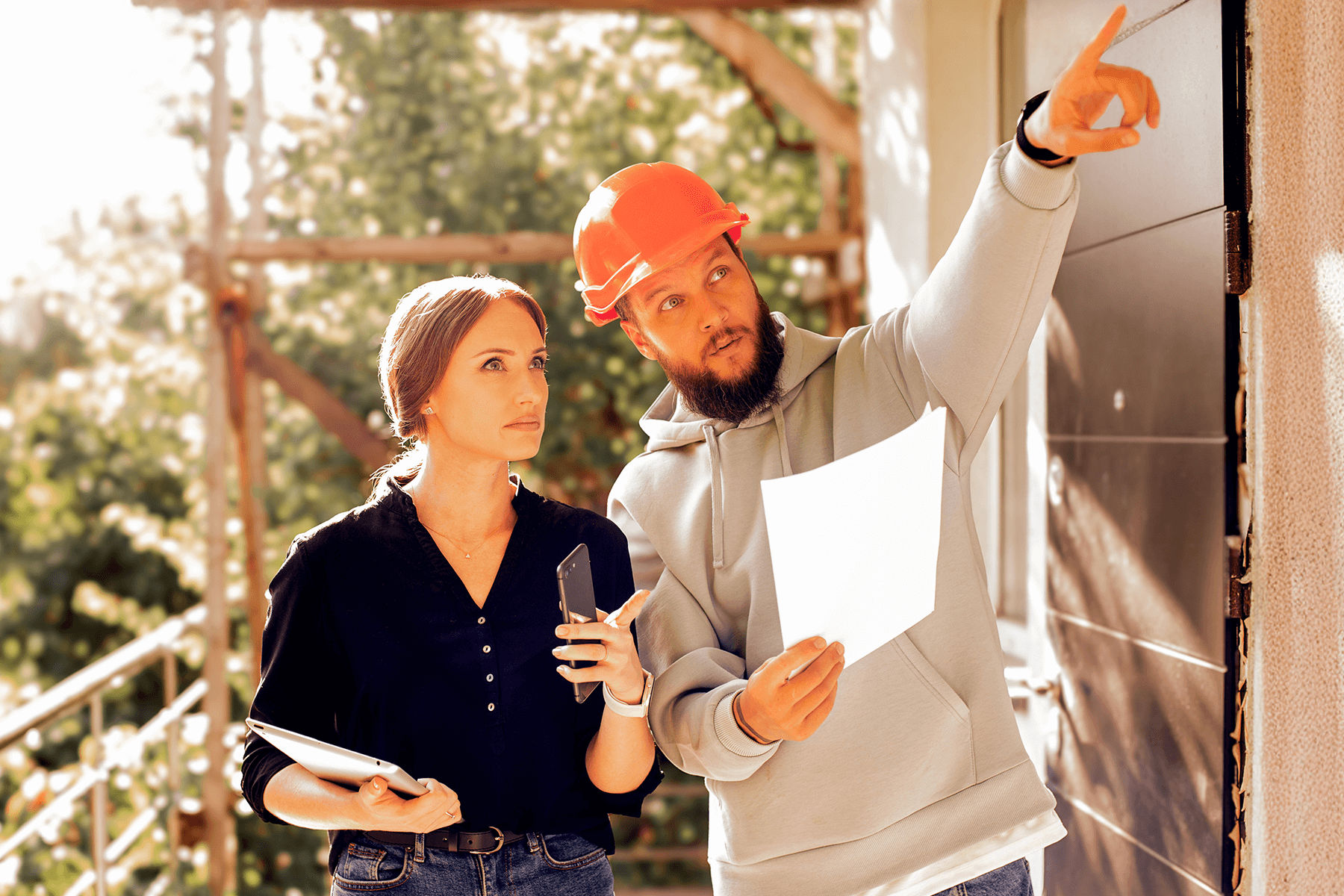 Zwei Personen mit Helm besprechen Pläne auf einer Baustelle, Ausdruck für professionelle Bauleitung durch HIS Hausbau