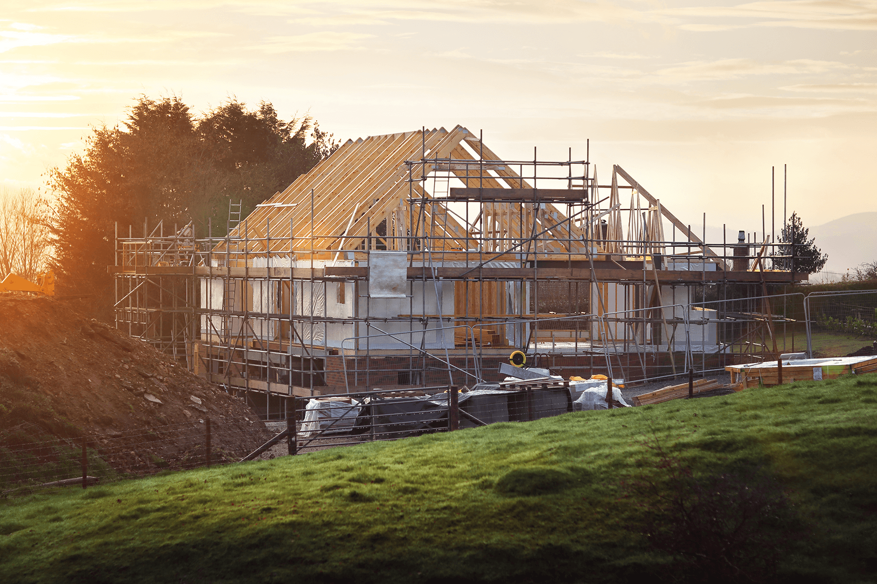 Haus im Rohbau mit Dachstuhl im Abendlicht, steht für massive Bauweise Stein auf Stein und Qualität