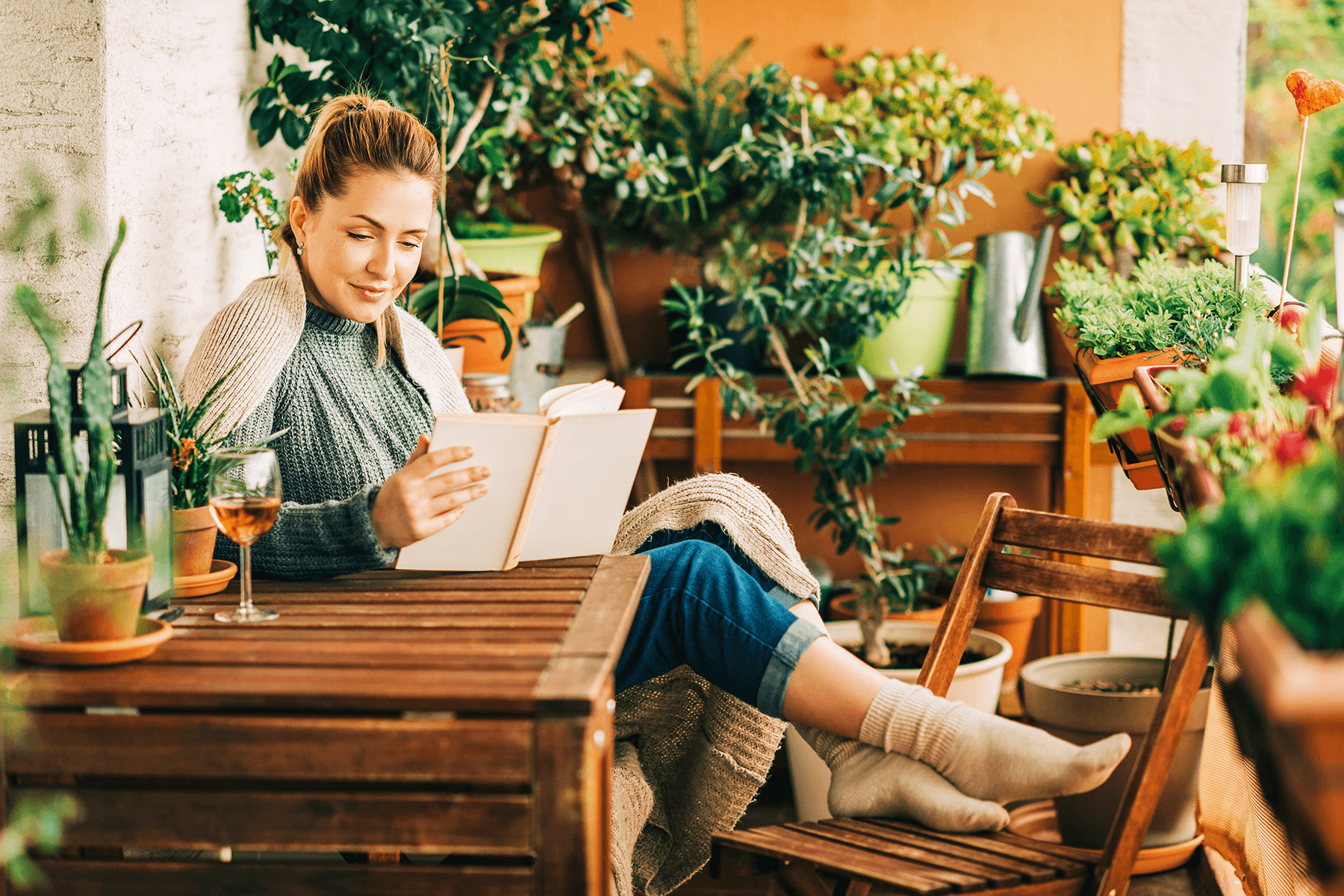 Person arbeitet entspannt auf einer Holzterrasse mit Laptop. Beispiel für Wohnen und Arbeiten in natürlicher Umgebung.