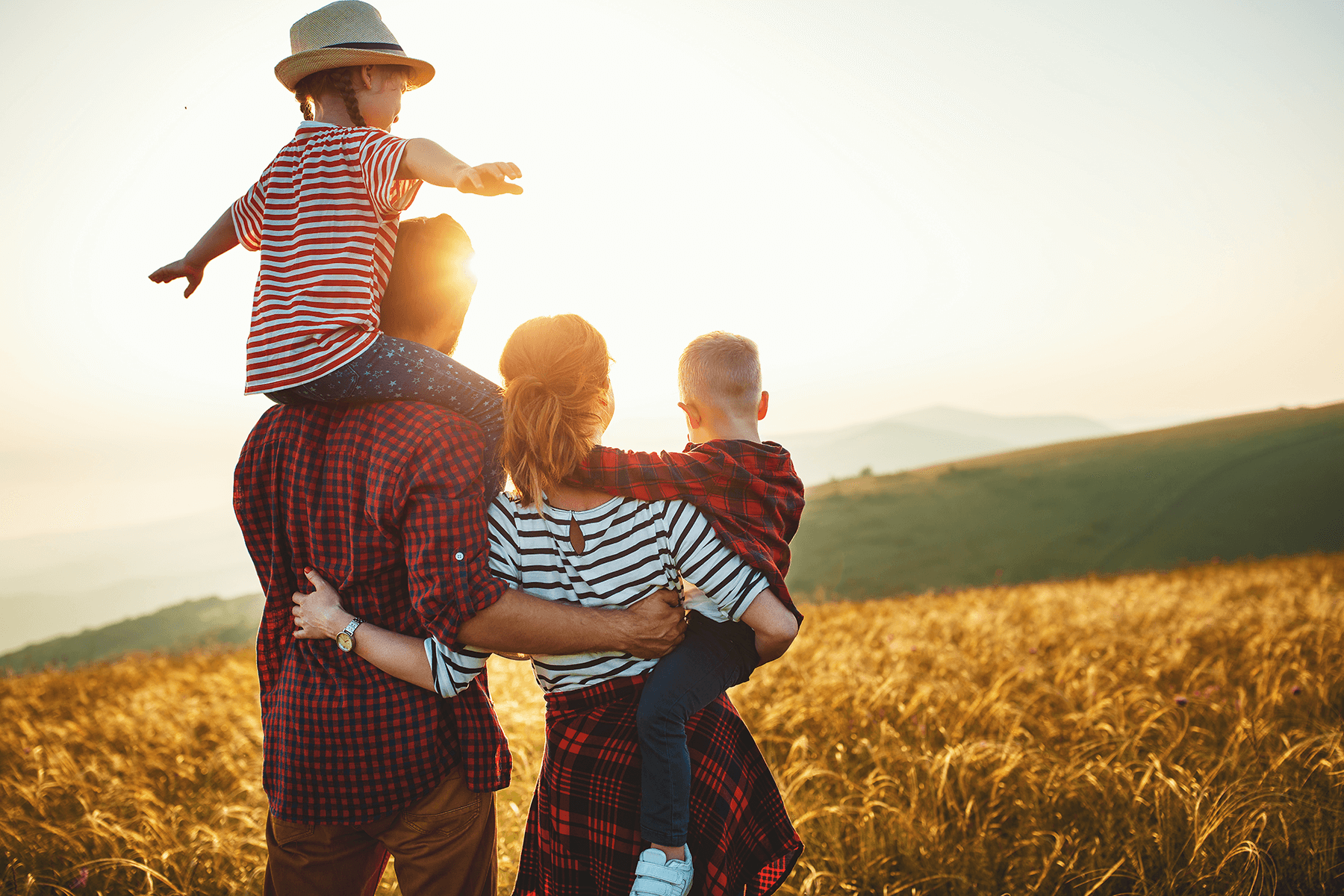 Familie mit Kind blickt in die Ferne über ein goldenes Feld, Sinnbild für Freiheit und Zukunft mit dem eigenen Bungalow