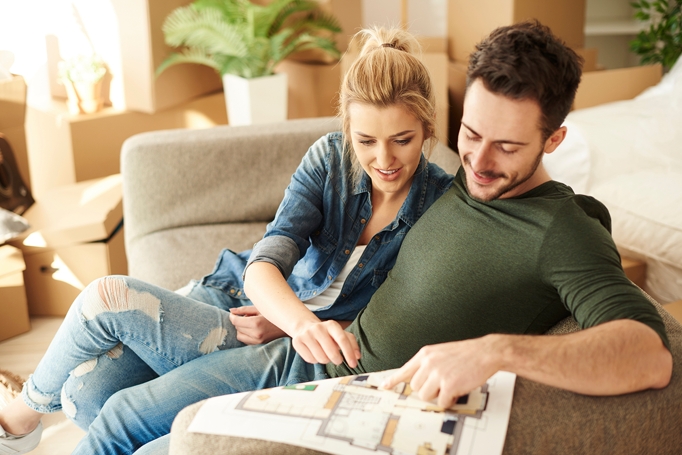 Paar liest entspannt auf der Couch einen ausgedruckten Grundriss. Maximale Individualität.