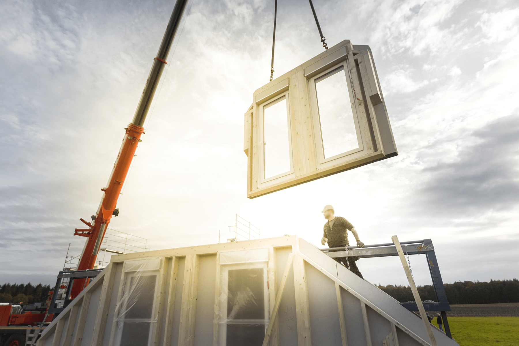 Montage einer Hauswand per Kran auf der Baustelle – moderne Fertigbauweise mit präziser Vorfertigung und energieeffizientem Wandaufbau.