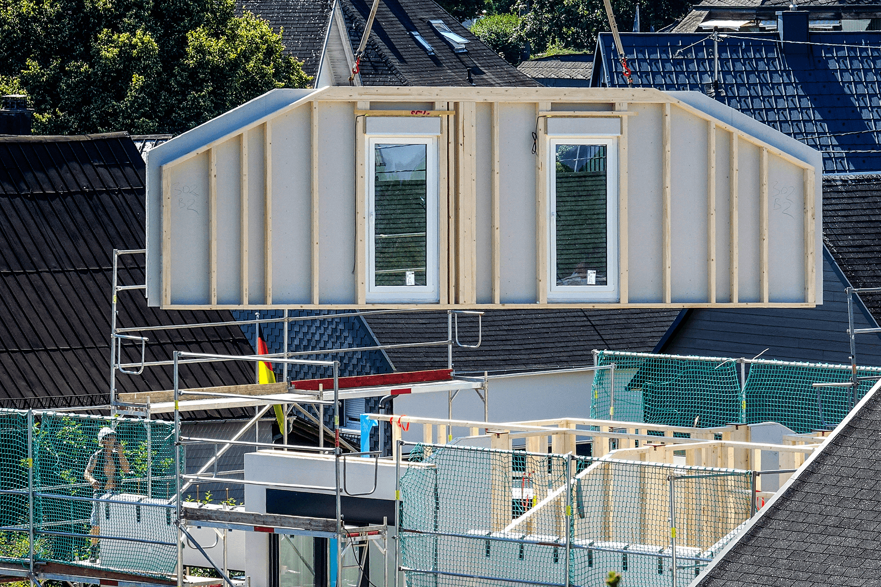 Dachwand eines Hauses wird mit Kran montiert – energieeffiziente Bauweise mit vorgefertigten Elementen.
