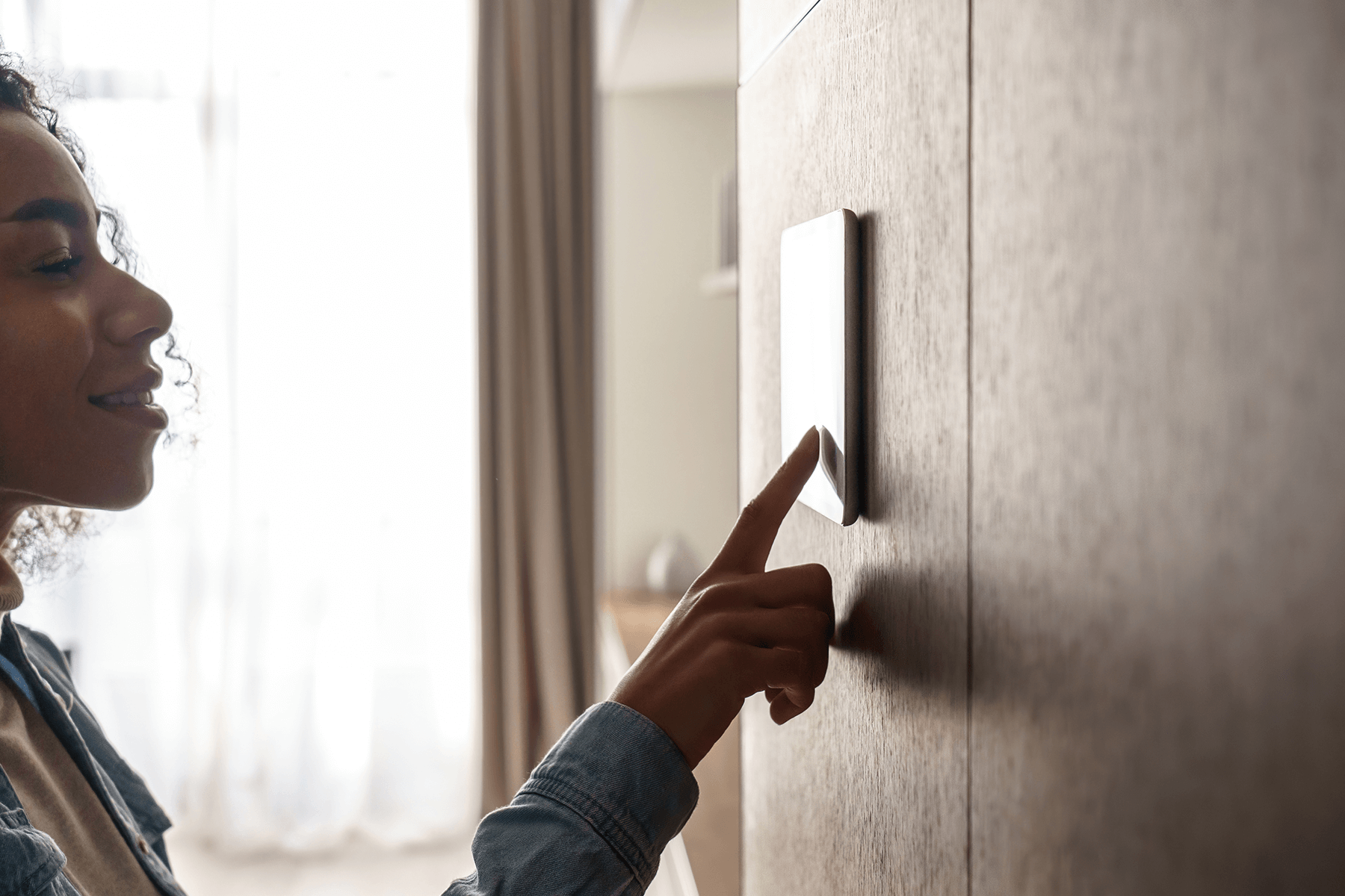 Person bedient ein Smart-Home-Bedienfeld im modernen Bungalow – smarte Haustechnik für Komfort und Energieeffizienz.