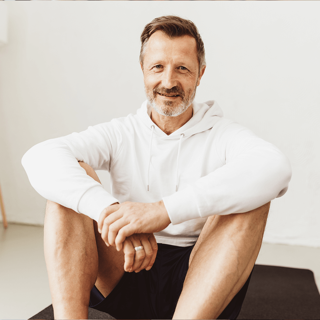 Mann in Sportkleidung sitzt entspannt nach dem Training in einem hellen Raum – Sinnbild für Gesundheit und Wohlbefinden im Zuhause