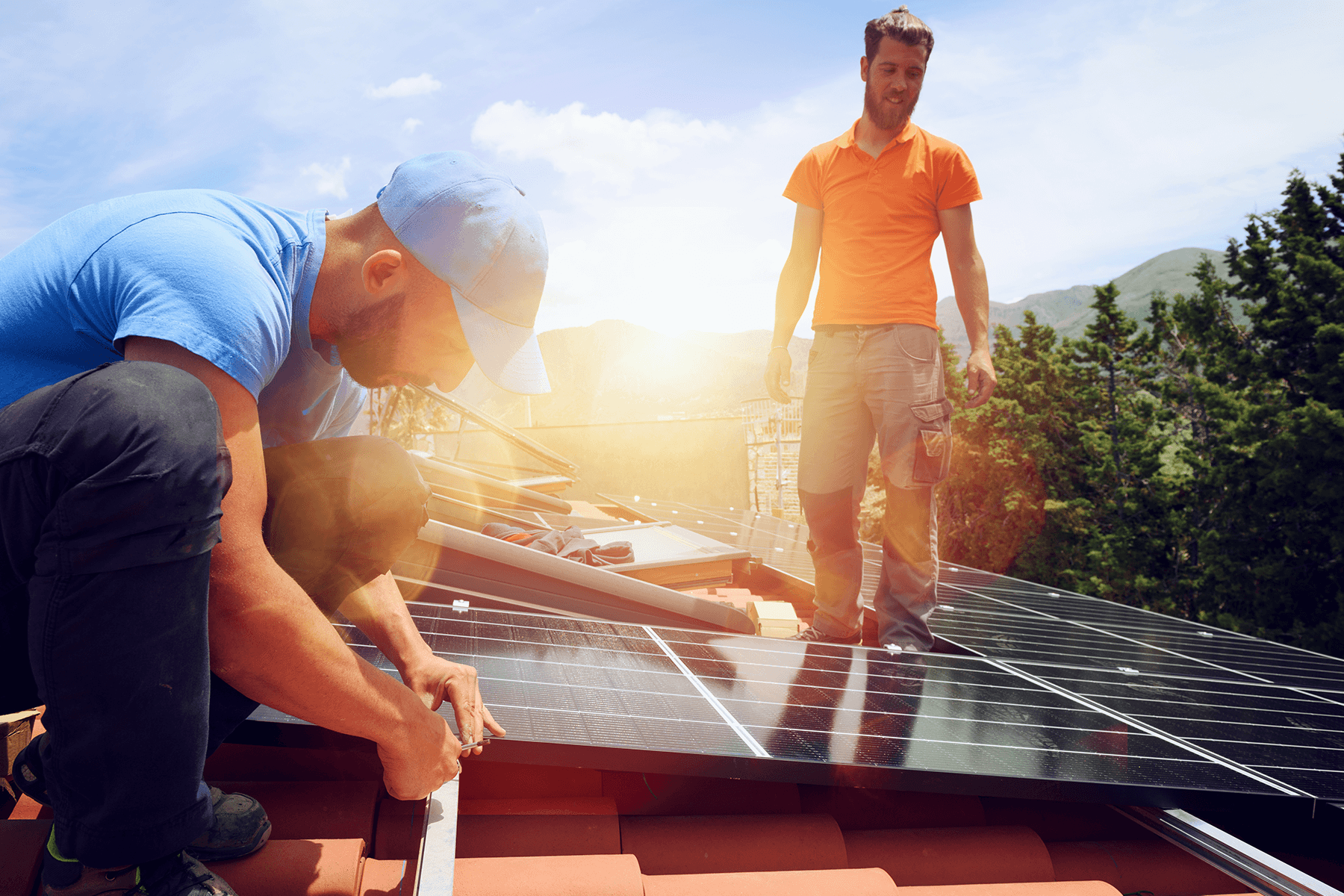 Zwei Handwerker installieren eine Photovoltaikanlage auf einem Hausdach, nachhaltige Energiegewinnung beim Neubau.