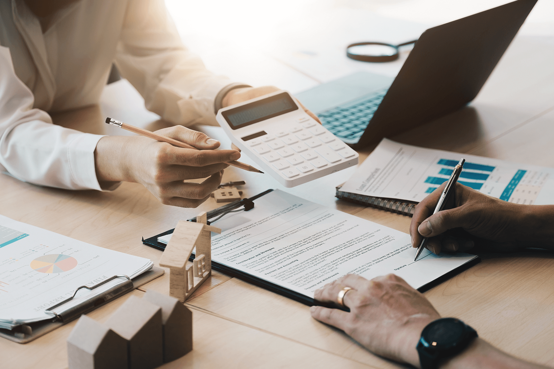 Kostenübersicht und Finanzplanung für den Bungalowbau mit Taschenrechner und Hausmodell.